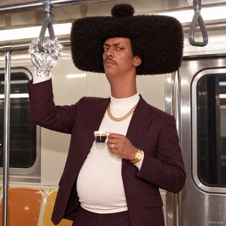 Phil in burgundy suit standing in a subway car, gripping the overhead strap with an oversized crystalline diamond hand while his other hand holds an espresso, passengers omitted, totally indifferent face, candid flash photo.